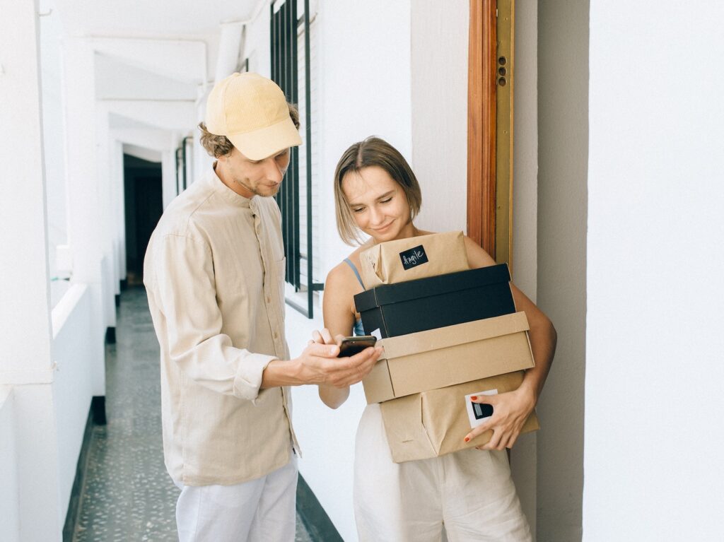 A Woman Receiving Her Parcels while Standing Beside the Delivery Man