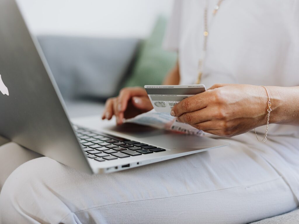 Person Using a Macbook and Holding a Credit Card