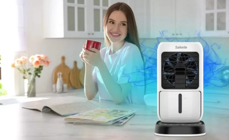 Žena sedí u stolu a ochlazuje se ochlazovačem vzduchu