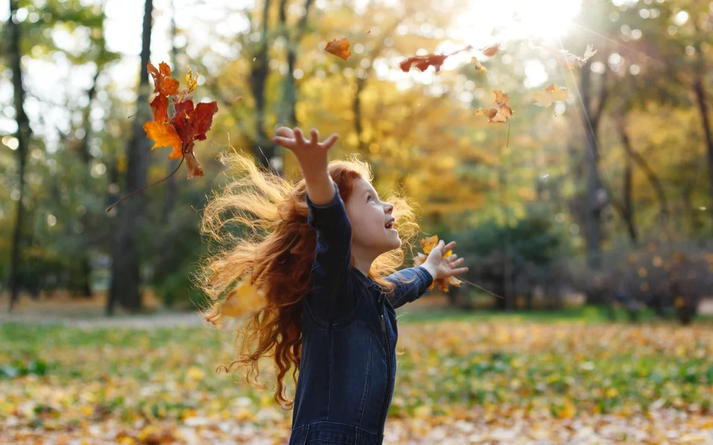 Dítě si hraje venku s listím