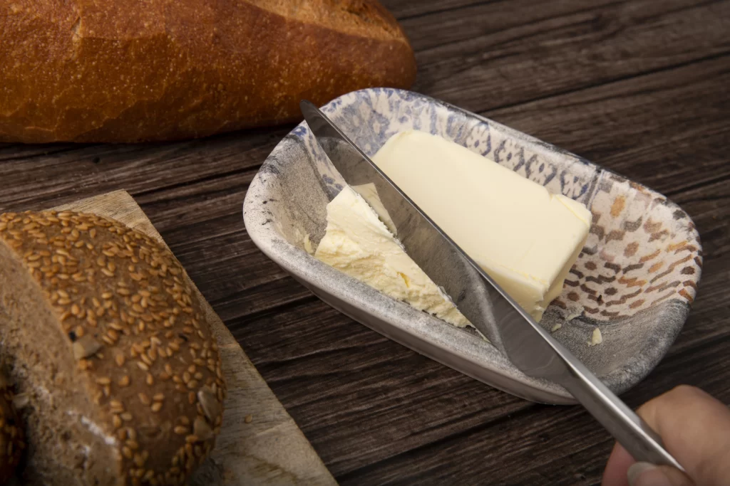 Osoba krájí máslo příborovým nožem