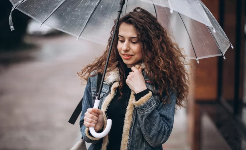 Žena s deštníkem stojí na chodníku