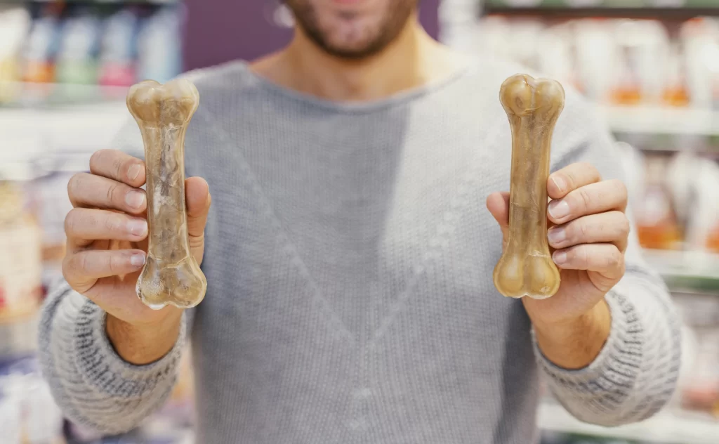 Člověk drží v ruce nezdravé buvolí kosti, pamlsky pro psy