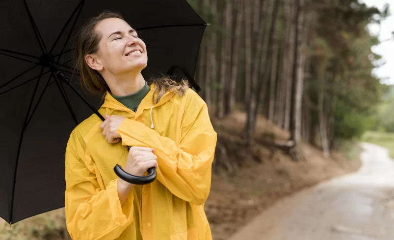 Žena s deštníkem se usmívá, i když venku prší