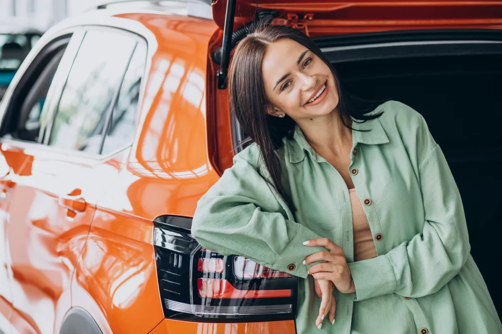 Šťastná žena stojí u svého automobilu