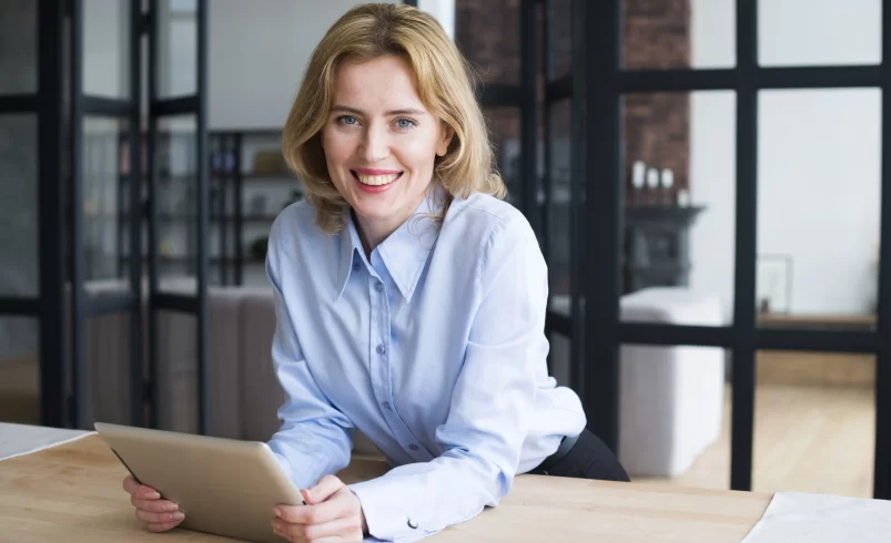 Usměvavá žena sedí u pracovního stolu