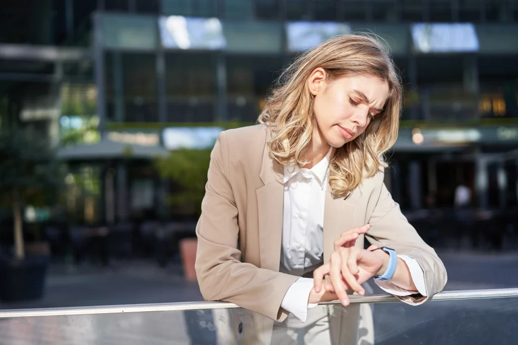 Žena se dívá na hodinky a zjišťuje, že je v časovém skluzu