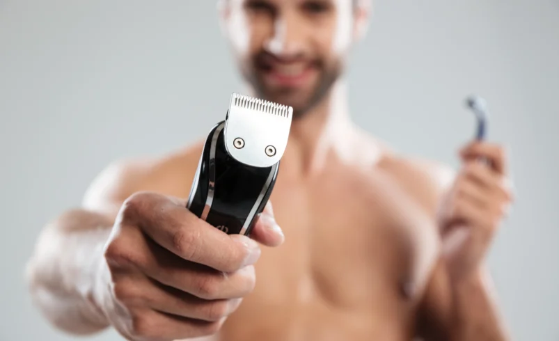 Muž má v ruce holicí strojek