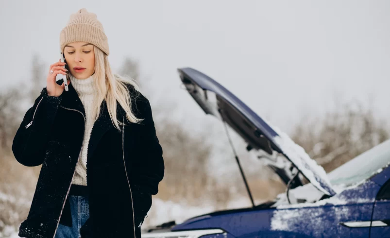 Žena stojí u auta a telefonuje