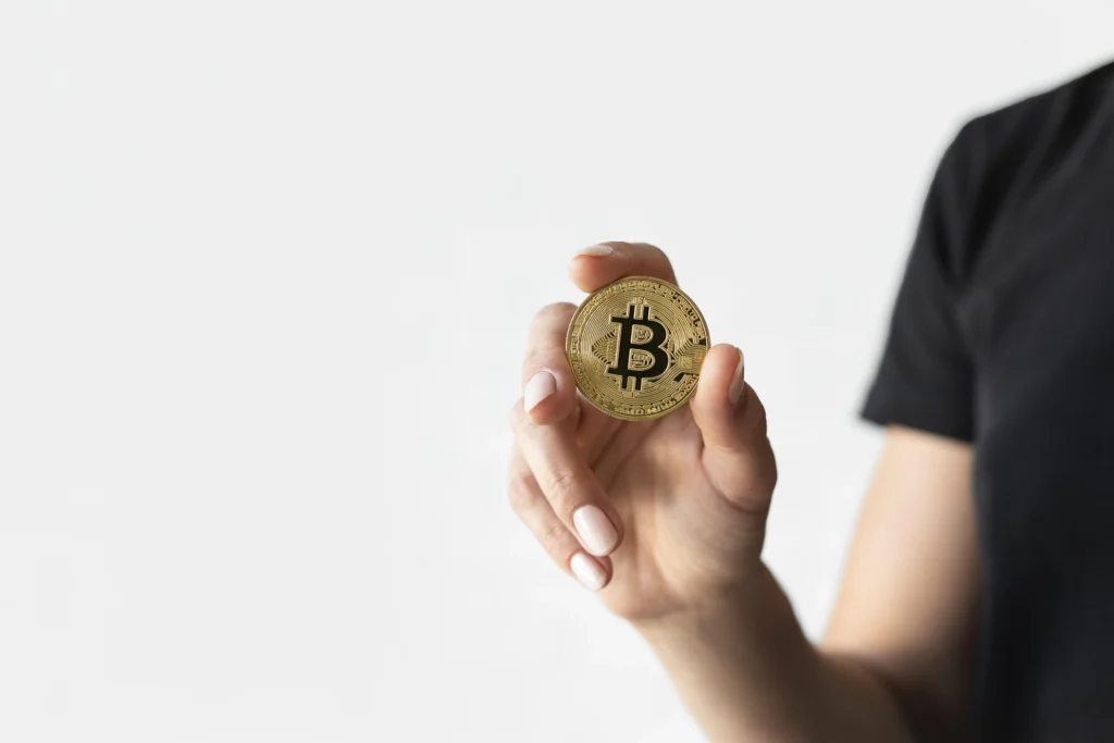 Žena drží sběratelskou minci Bitcoin