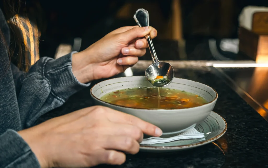 Člověk pojídá polévku v restauraci